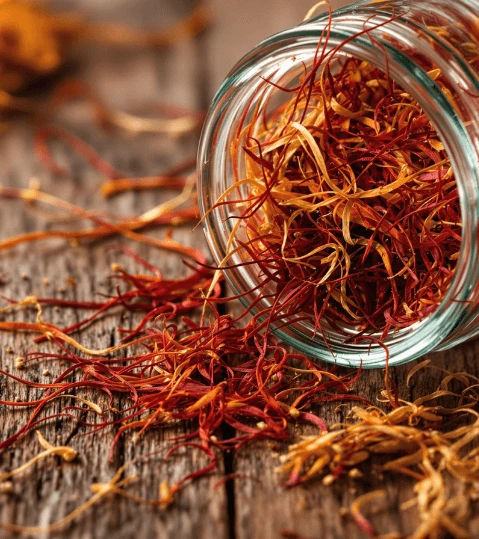 Fils de safran dans un pot en verre sur table en bois
